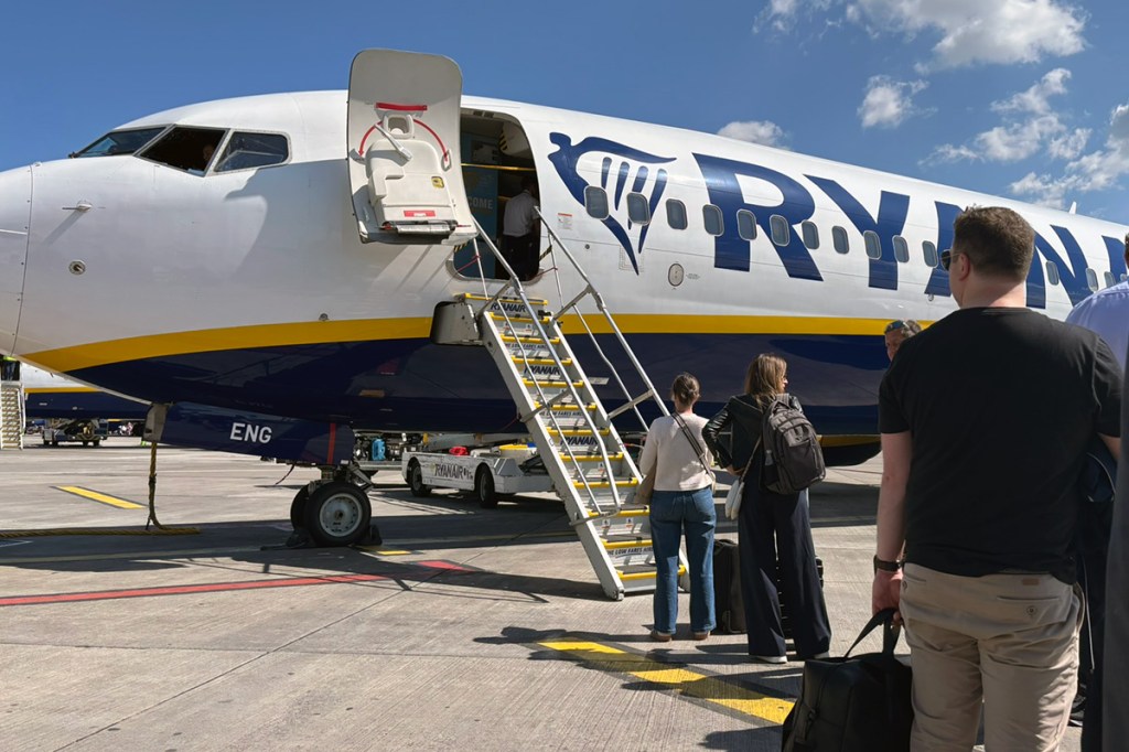 people in line waiting to walk up steps to board an aircraft